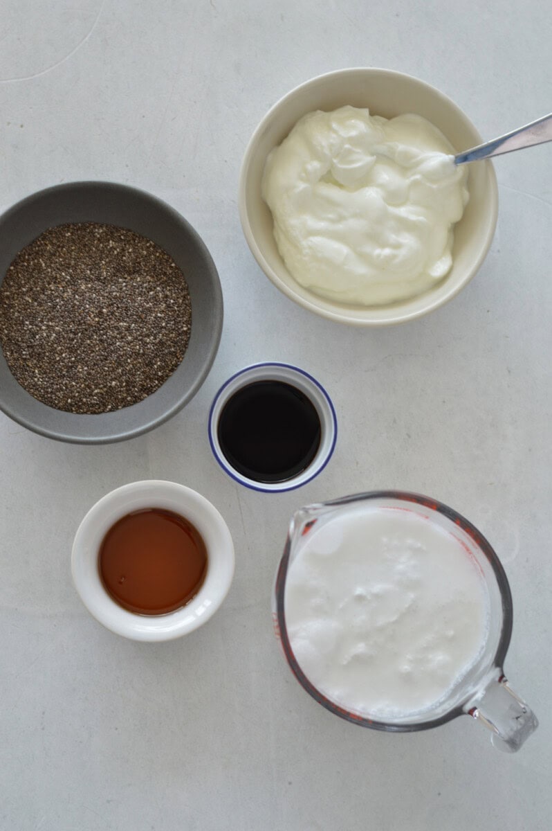 Birds eye of ingredients including greek yogurt, chia seed, coconut milk, vanilla and maple syrup.