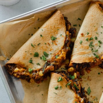 Close up of crispy baked black bean tacos on a sheet pan.