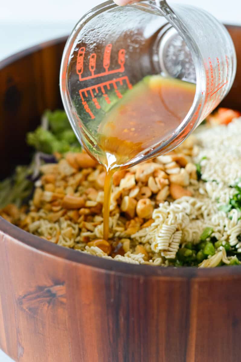 Drizzling dressing over broccoli coleslaw salad.