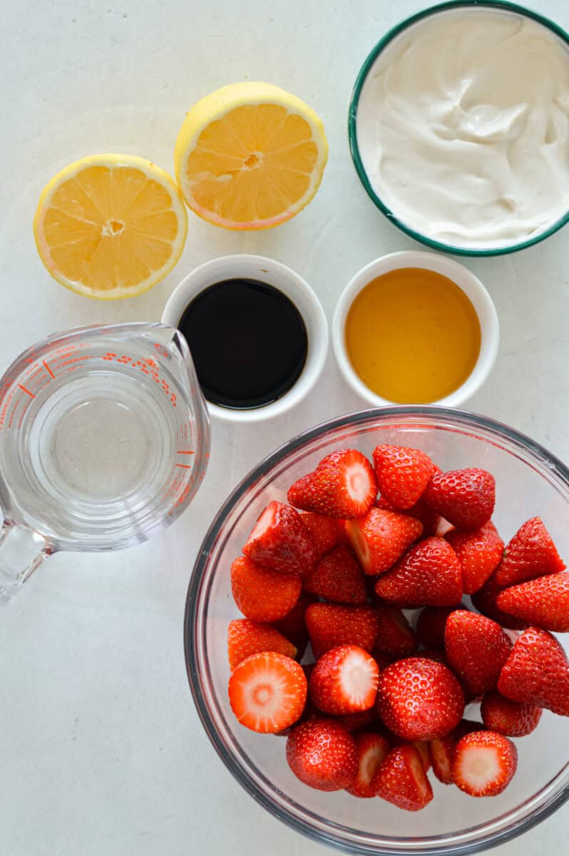 Birds eye of ingredients like strawberries, lemon, water, greek yogurt, honey and vanilla extract.