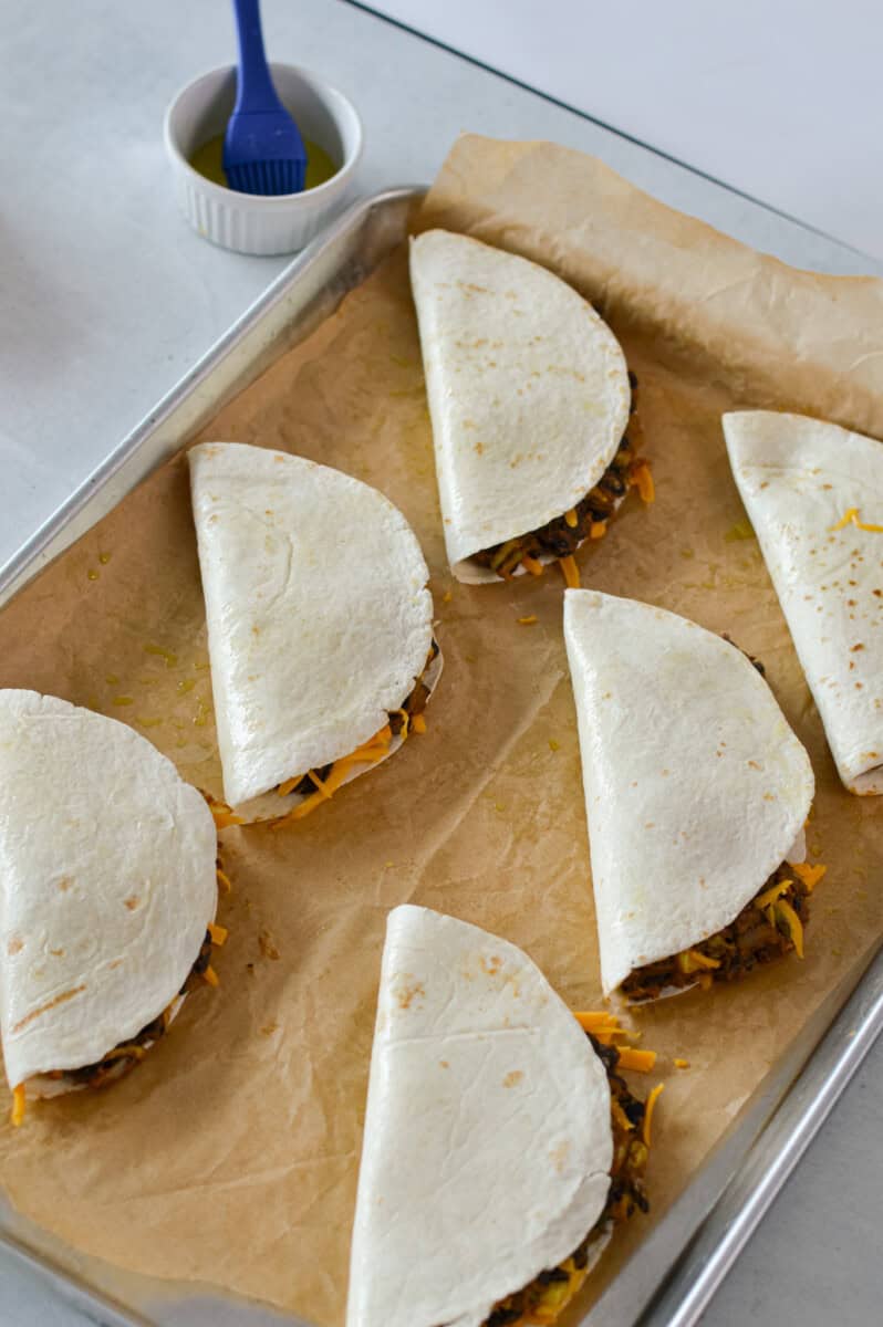 Folded black bean tacos on a baking tray.