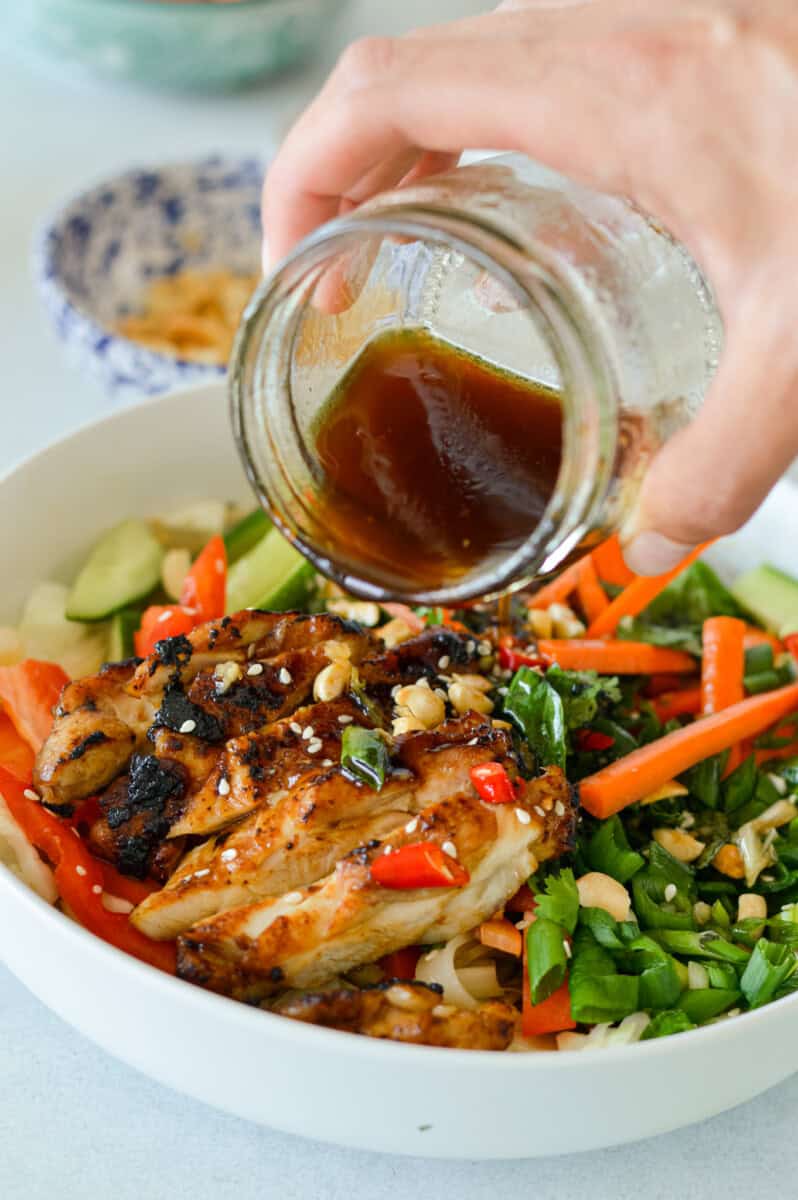 Adding dressing to spring roll teriyaki chicken bowls