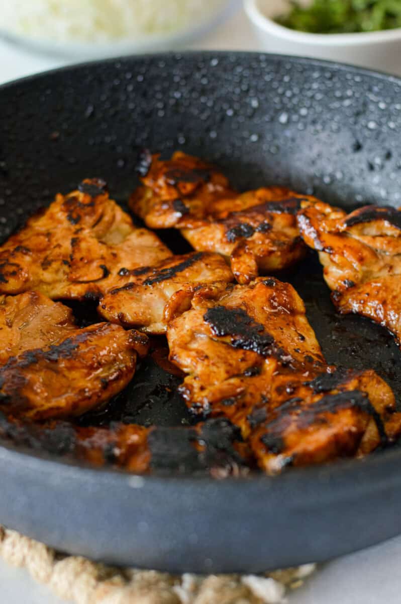 Cooking teriyaki chicken thighs on a pan.