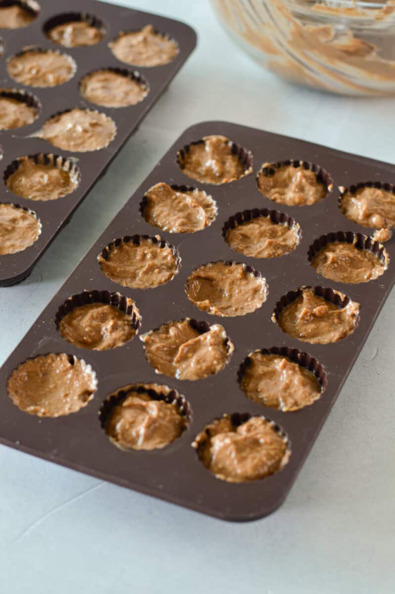 Filling an ice cube tray with peanut butter yogurt mixture.