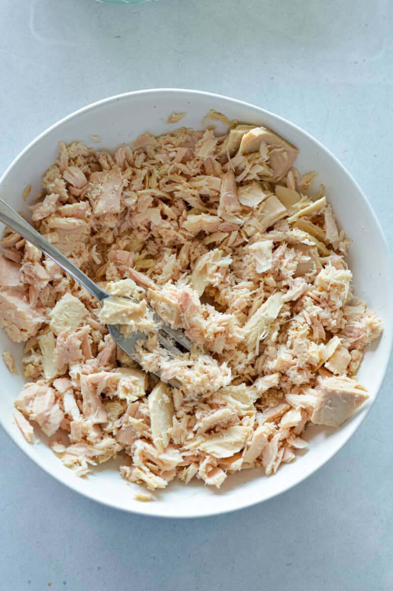 Flaking canned tuna in a bowl.