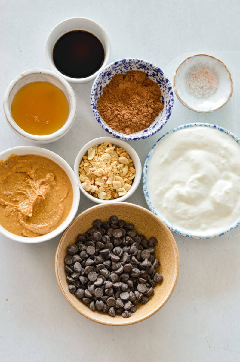 Ingredients including peanut butter, greek yogurt, honey, peanuts, chocolate chips, vanilla and chopped peanuts.