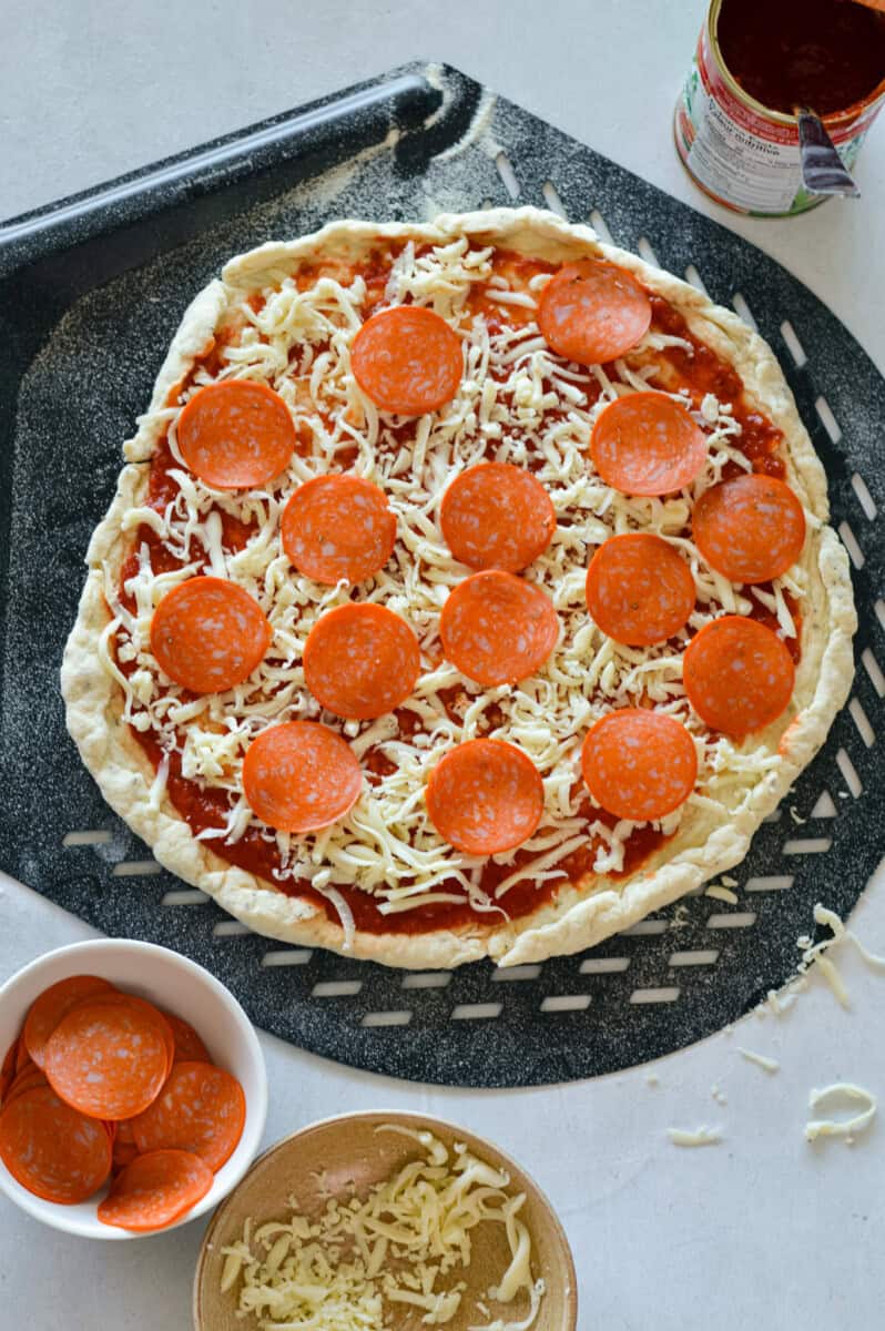 Adding cheese and pepperoni to Greek yogurt pizza dough crust.
