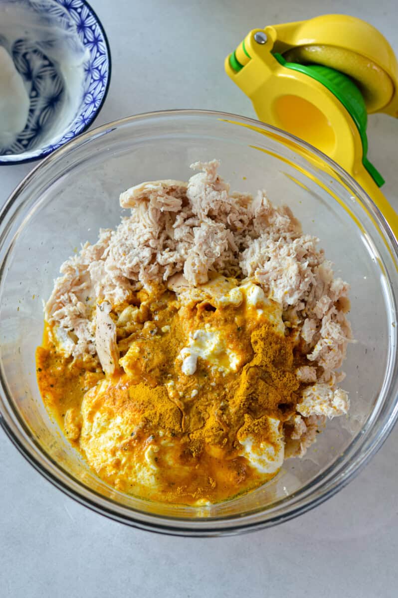 Mixing shredded chicken with spices and curry dressing.