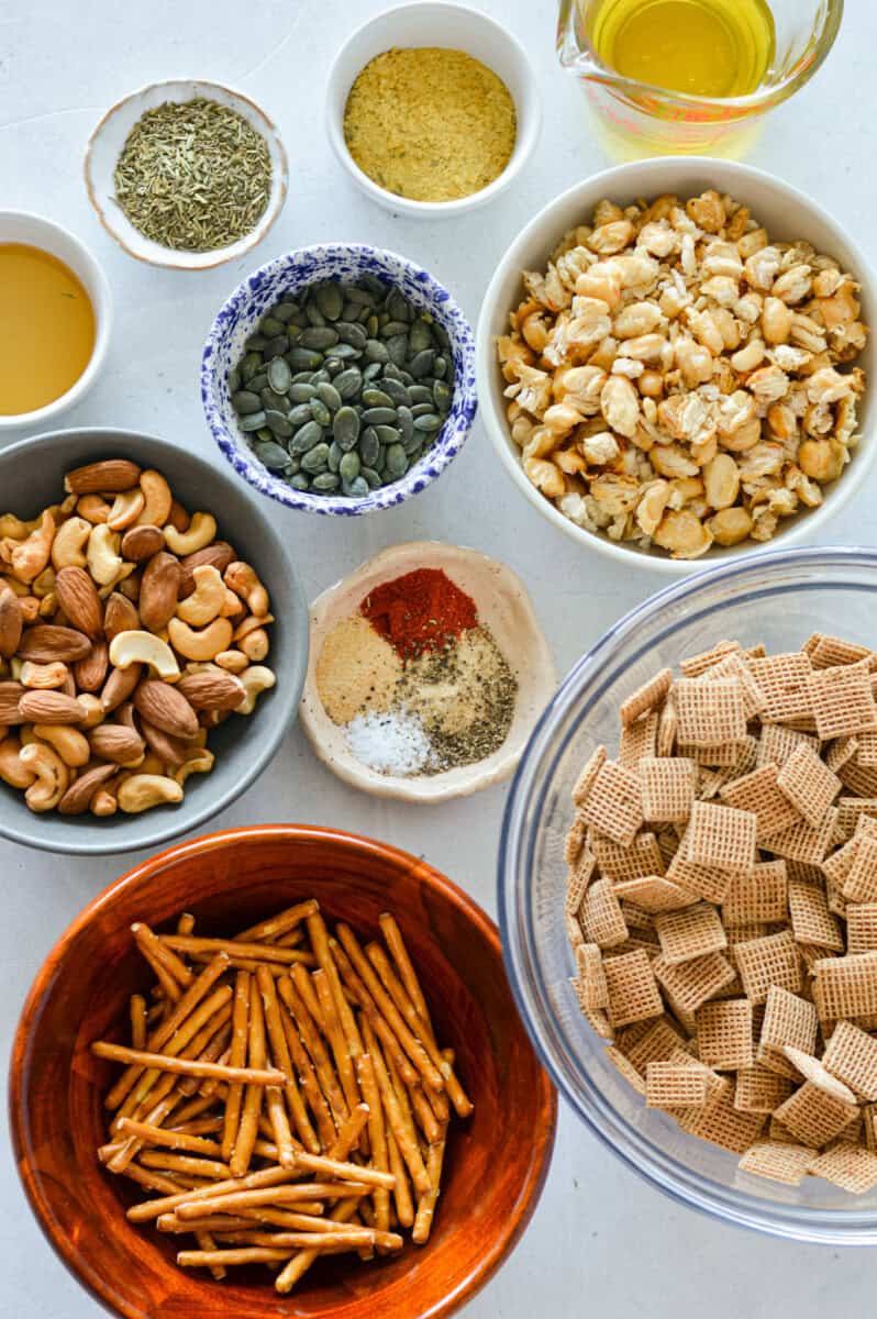 Ingredients including chex cereal, pretzels, almonds, cashews, spices, herbs, olive oil, honey and beans.