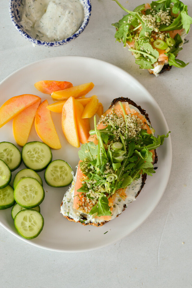 Birds eye of a plate with ricotta toast, cucumbers and peaches.