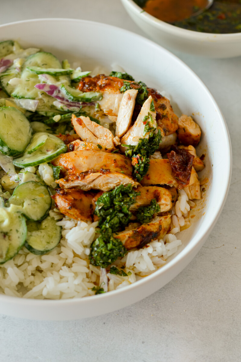 Bowl of chipotle chicken with rice and creamy cucumber salad.