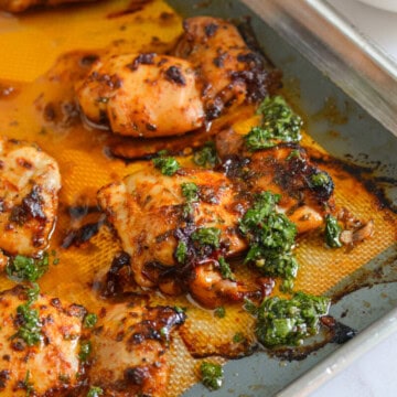 Close up of chipotle chicken on a tray, topped with chimichurri.