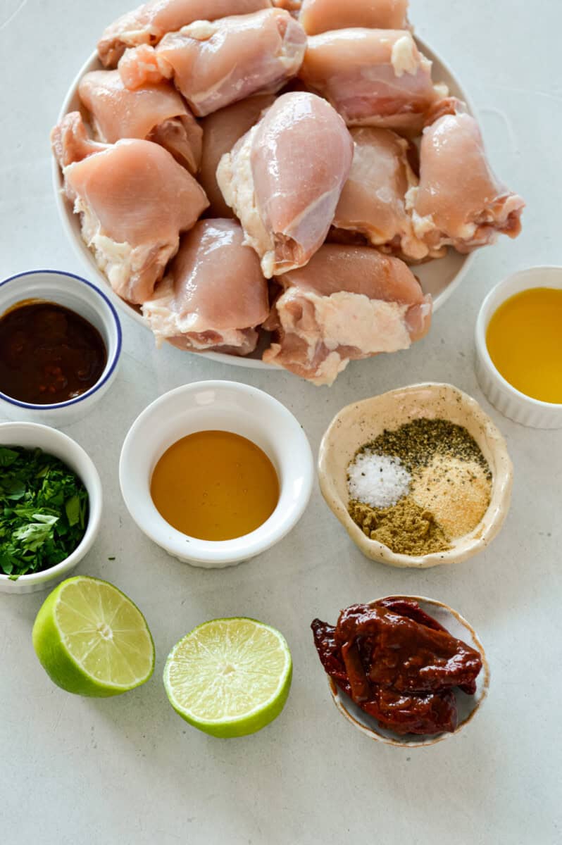 Ingredients including chicken thighs, lime, parsley, honey, spices and olive oil.
