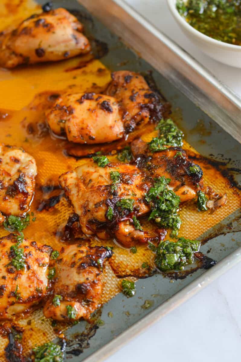 Close up of chipotle chicken on a tray, topped with chimichurri.