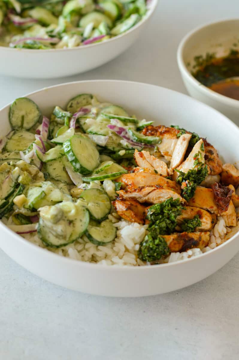 Bowl of cucumber salad, rice and chicken.
