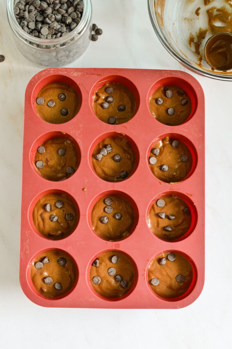 Silicone muffin tray with chocolate and zucchini muffin batter.
