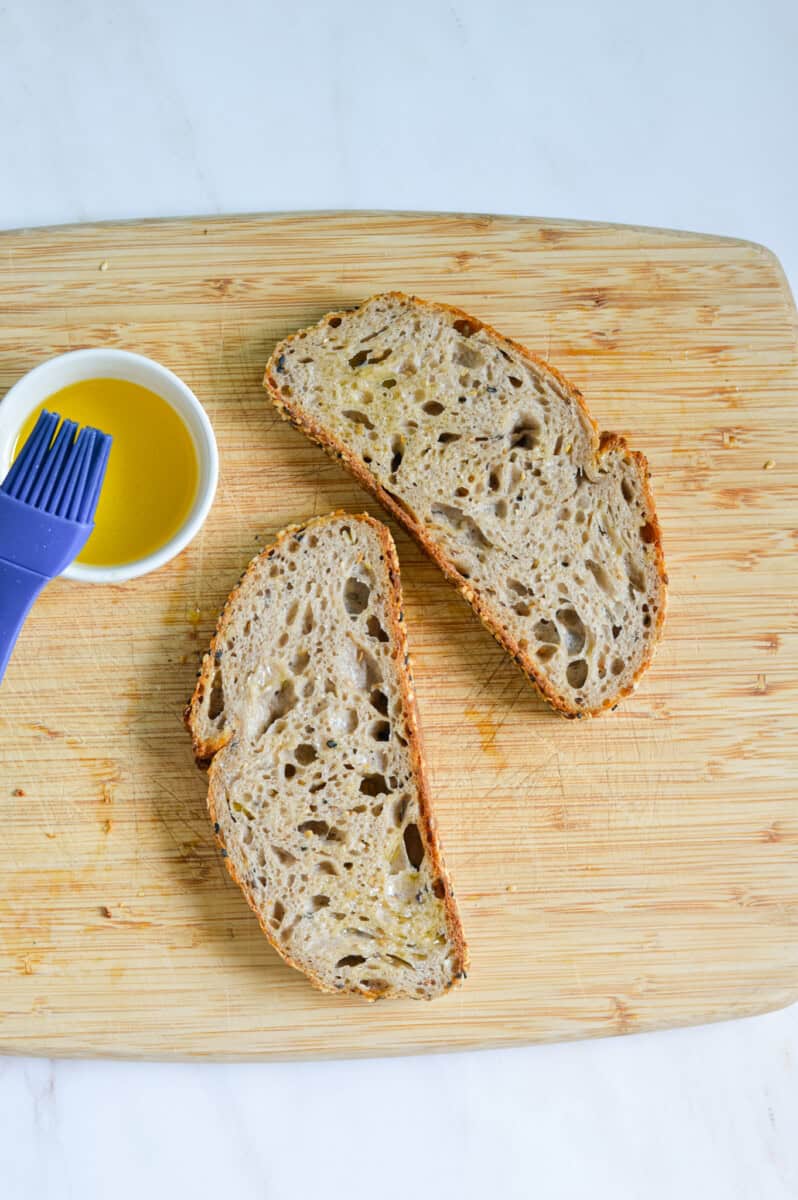 Brushing two slices of bread with olive oil.