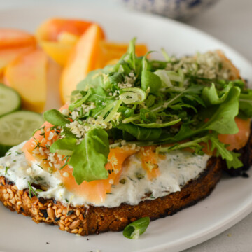Slice of toast with whipped ricotta cheese, smoked salmon and arugula.